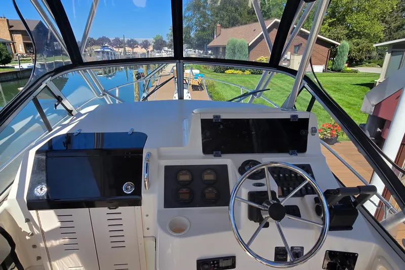Slide: The Image of 2003 Grady-White Sailfish 282 helm with steering wheel and instrument panel, docked by a canal. - 6