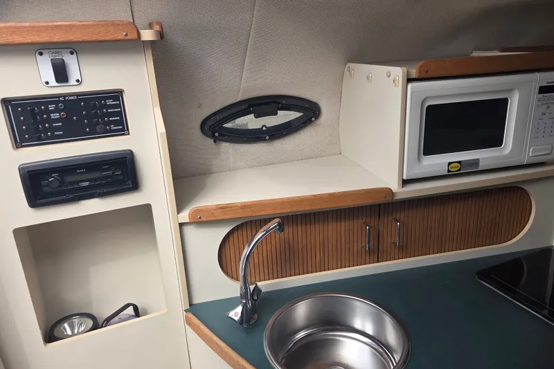 Slide: The Image of 1999 Four Winns 258 Vista boat interior with kitchenette, microwave, sink, and control panel. - 13