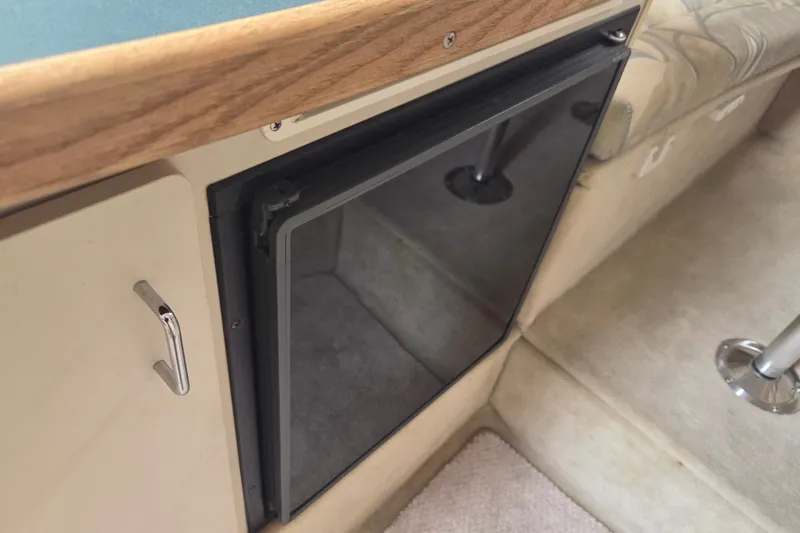 Slide: The Image of 1999 Four Winns 258 Vista cabin interior with compact refrigerator and seating area. - 14