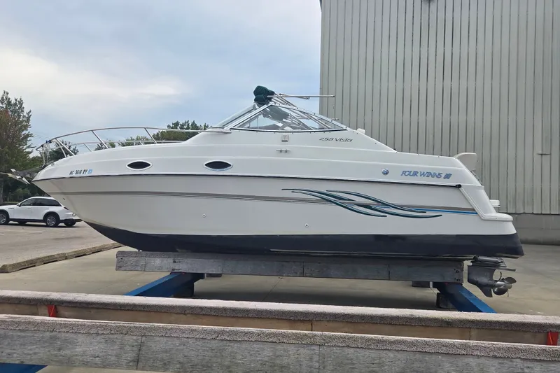 The Image of 1999 Four Winns 258 Vista boat on trailer, parked outdoors near a building. - 0