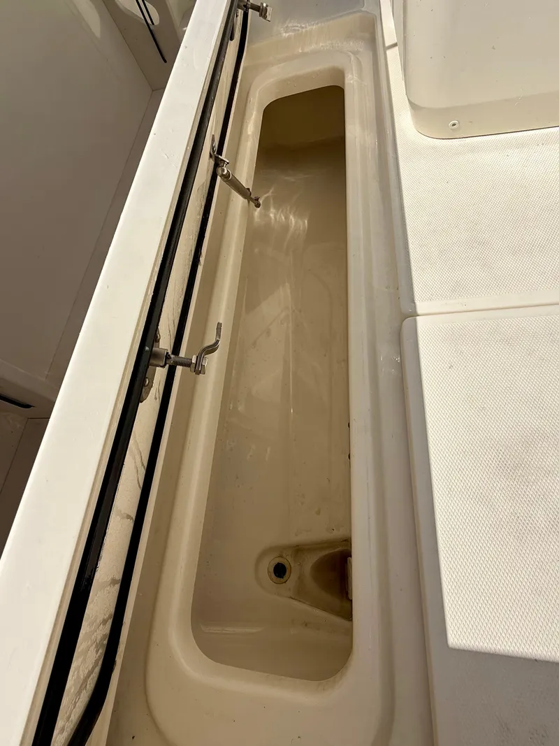 Slide: The Image of 2024 Boston Whaler 250 Outrage: Long, rectangular storage compartment with drain and metal latches. - 33