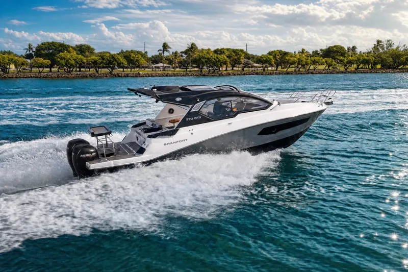 Slide: The Image of 2026 Granfort 370 GTX luxury boat cruising on blue water near a scenic shoreline. - 13