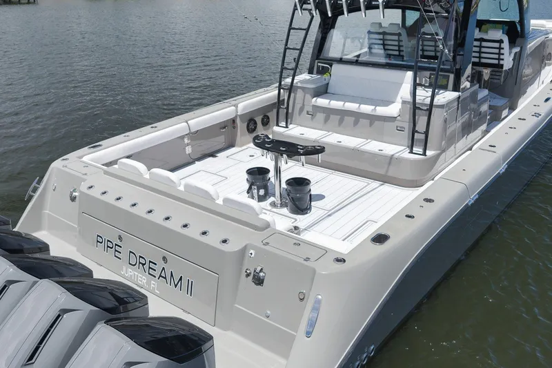 Slide: The Image of 2023 HCB 65 Estrella luxury boat docked, featuring spacious deck and seating area. - 22