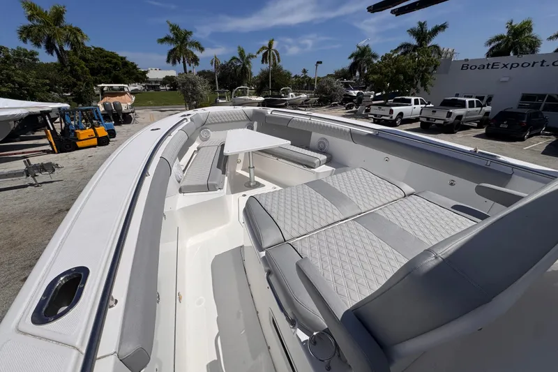 Slide: The Image of 2016 Everglades 435 Center Console boat with spacious seating and table, parked outdoors. - 8