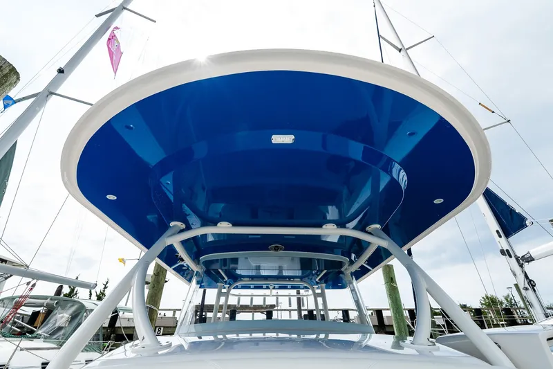Slide: The Image of 2021 Jupiter 43 boat with blue canopy, docked under a cloudy sky. - 35