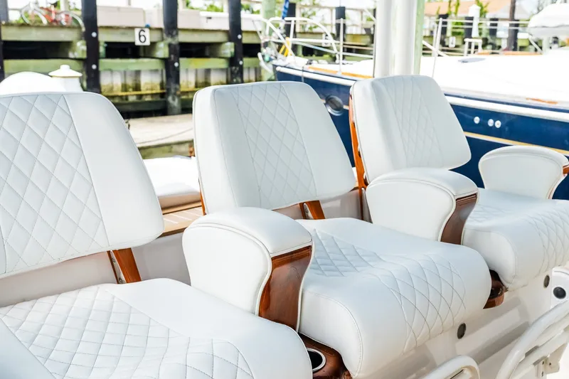 Slide: The Image of Luxurious white leather seats on a 2021 Jupiter 43 boat, docked at a marina. - 38
