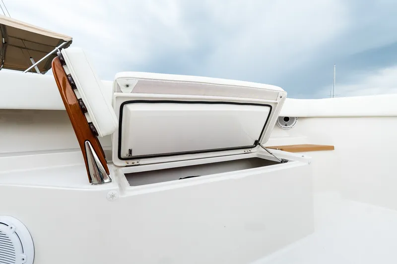 Slide: The Image of Open storage compartment on 2021 Jupiter 43 boat, featuring sleek white design and wooden accents. - 53