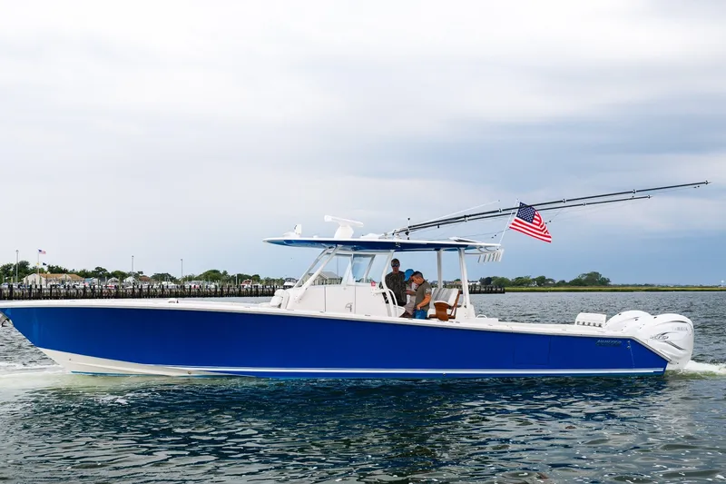 The Image of 2021 Jupiter 43 boat cruising on water, featuring a blue hull and American flag. - 0