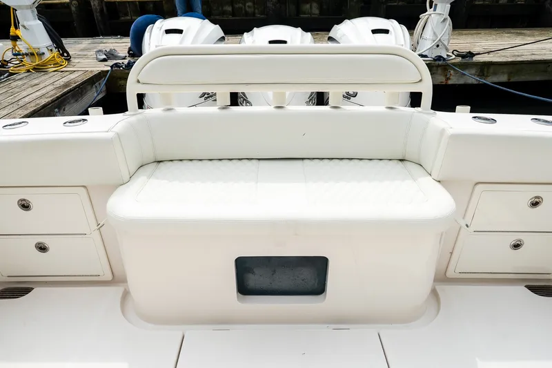 Slide: The Image of White seating area on a 2021 Jupiter 43 boat, docked with visible engines. - 16