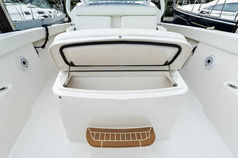 Slide: The Image of Open storage compartment on a 2021 Jupiter 43 boat deck, featuring white seating and speakers. - 28