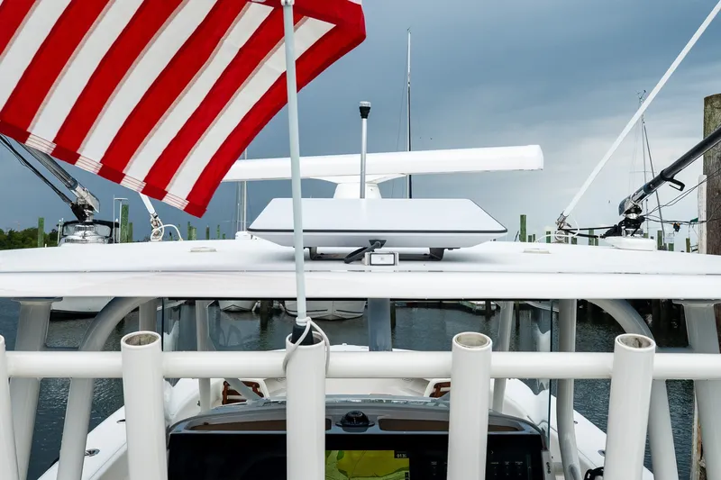 Slide: The Image of 2021 Jupiter 43 boat with American flag, docked under cloudy sky. - 34