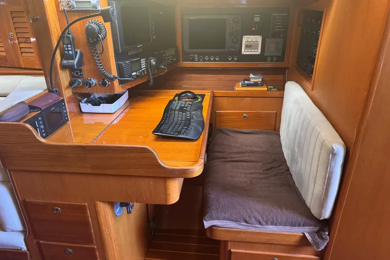 Slide: The Image of Navigation station inside a 2020 J Boats J/160 yacht, featuring communication equipment and a cushioned seat. - 18