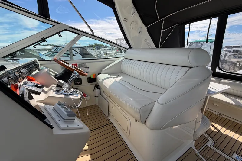 Slide: The Image of Das Bild zeigt das Cockpit einer Cruisers Yachts 3870 Express von 2000 mit weißen Ledersitzen und einem Holzlenkrad. - 9