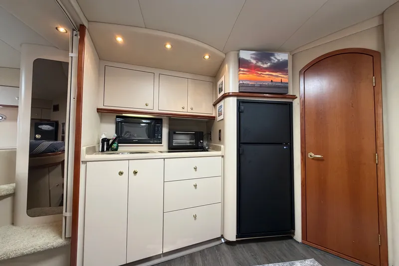 Slide: The Image of Interior of 2000 Cruisers Yachts 3870 Express, featuring kitchenette with cabinets and appliances. - 13