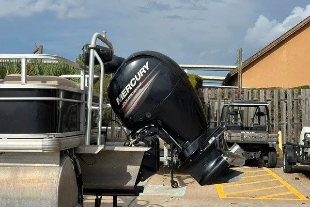 Slide: The Image of 2019 Sun Tracker Fishin' Barge 24 DLX with Mercury outboard motor in a parking area. - 16