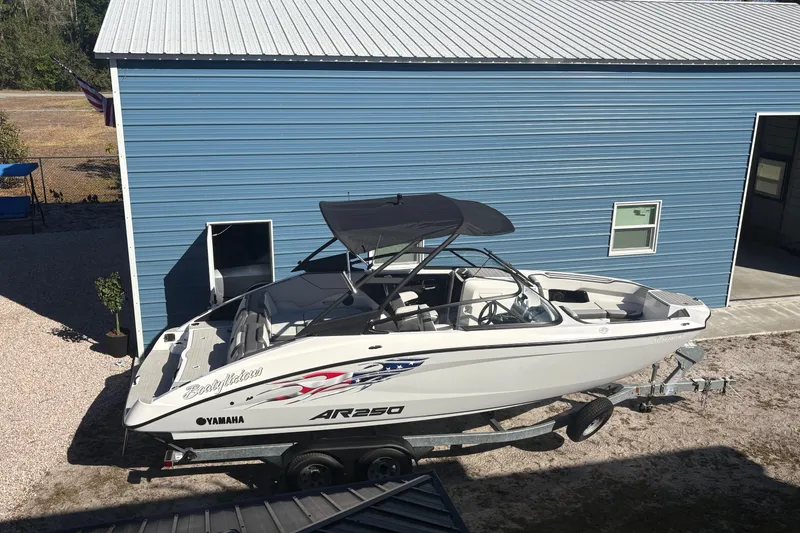 Slide: The Image of 2025 Yamaha AR250 boat on trailer beside blue building. - 4