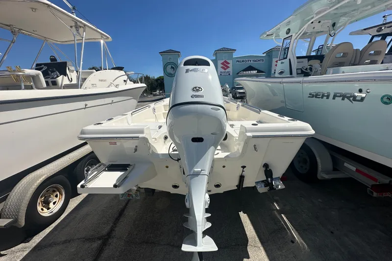 Slide: The Image of 2027 Bulls Bay 2000 XS boat with outboard motor, docked between other boats. - 4