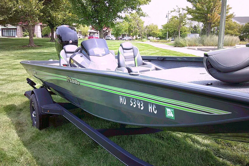 Slide: The Image of 2025 Ranger RT198P boat on trailer, parked on grass, with trees in background. - 6