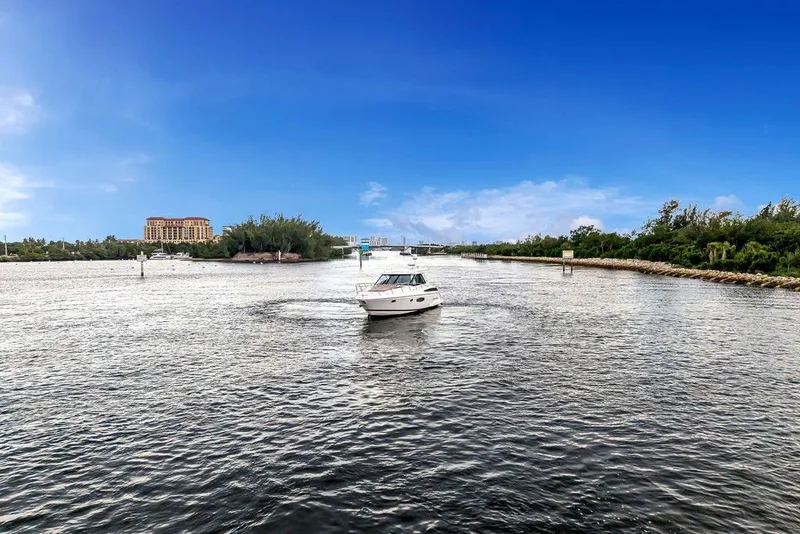 Slide: The Image of 2014 Regal 42 Sport Coupe cruising on a scenic waterway under a clear blue sky. - 23