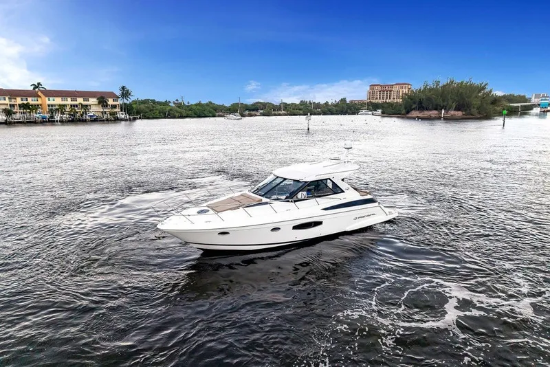 Slide: The Image of 2014 Regal 42 Sport Coupe cruising on a scenic waterway under a clear blue sky. - 24