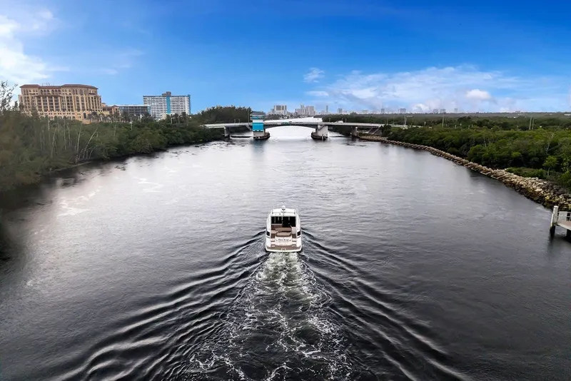 Slide: The Image of 2014 Regal 42 Sport Coupe cruising on a scenic river with cityscape backdrop. - 35