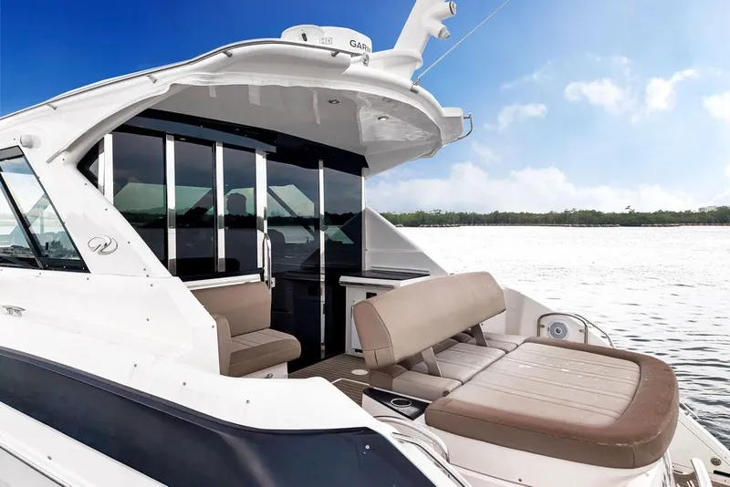 Slide: The Image of 2014 Regal 42 Sport Coupe yacht with spacious seating, cruising on a serene lake under a clear sky. - 31