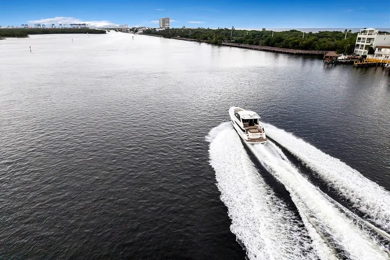 Slide: The Image of 2014 Regal 42 Sport Coupe cruising on a wide river, leaving a wake behind. - 29