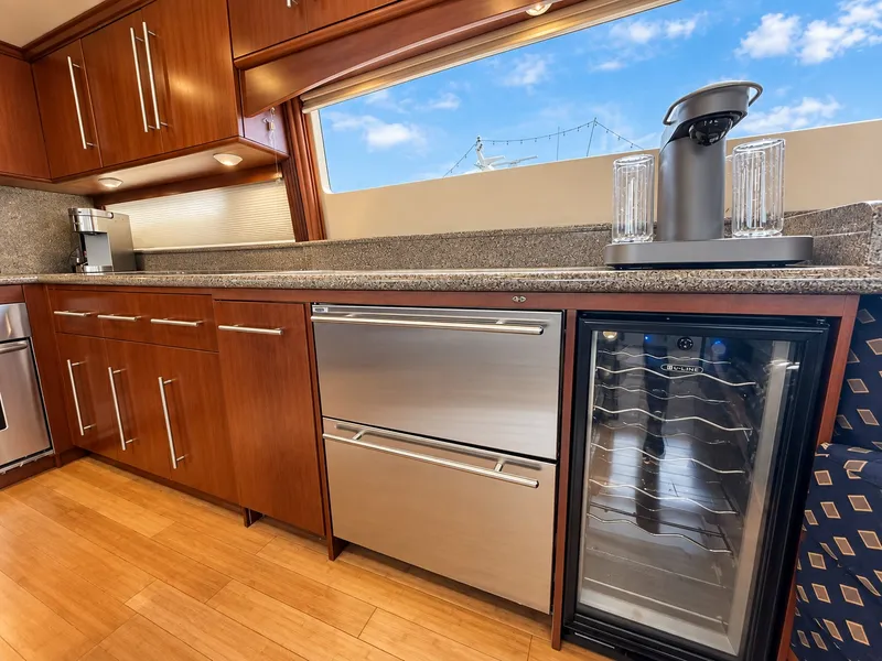 Slide: The Image of The 2002 Lazzara 80 Skylounge kitchen features elegant wood cabinets, a wine cooler, and modern appliances. - 43