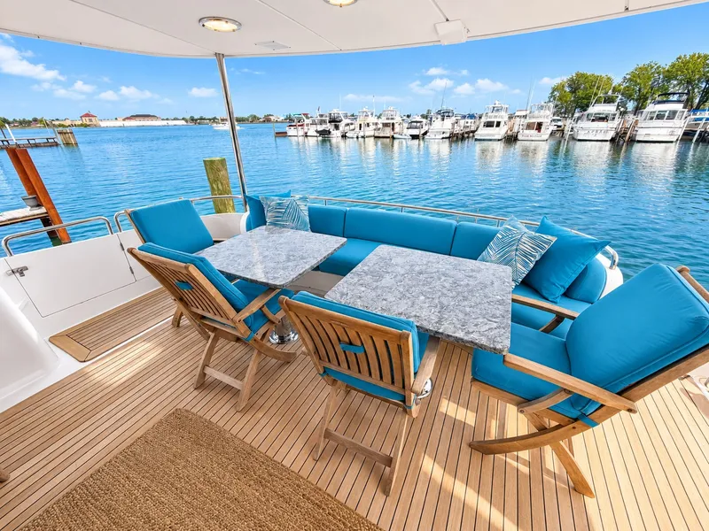Slide: The Image of The 2002 Lazzara 80 Skylounge features a spacious deck with blue cushions and wooden furniture. - 24