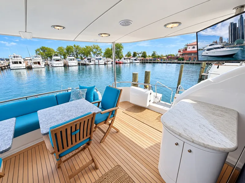 Slide: The Image of The 2002 Lazzara 80 Skylounge features an elegant deck with wood flooring, blue cushions, and a table. - 25