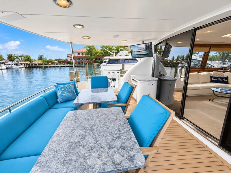 Slide: The Image of The 2002 Lazzara 80 Skylounge features an elegant outdoor deck with blue cushions and a view of the marina. - 27
