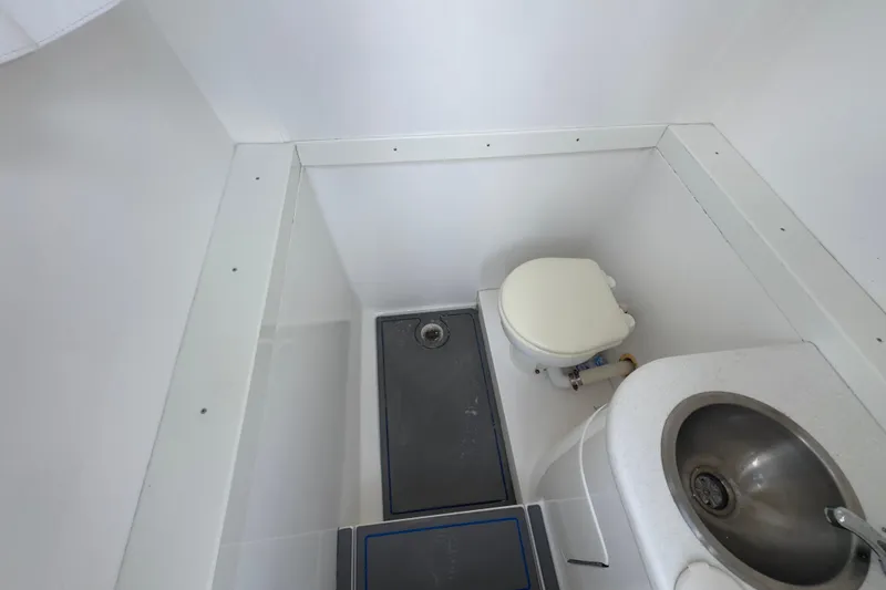 Slide: The Image of Compact bathroom in a 2007 Intrepid 370 Center Console boat, featuring a toilet and sink. - 90