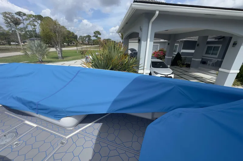 Slide: The Image of 2007 Intrepid 370 Center Console boat covered with blue tarp near modern house. - 94