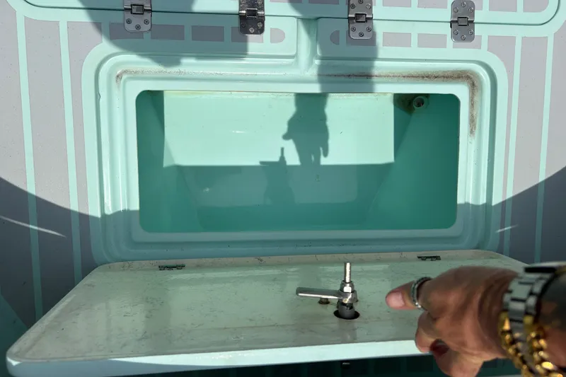 Slide: The Image of Open storage compartment on 2024 Exuma 22 boat with visible latch and hand. - 34