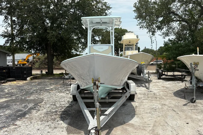Slide: The Image of 2024 Exuma 22 boat on trailer, parked outdoors with trees in the background. - 11