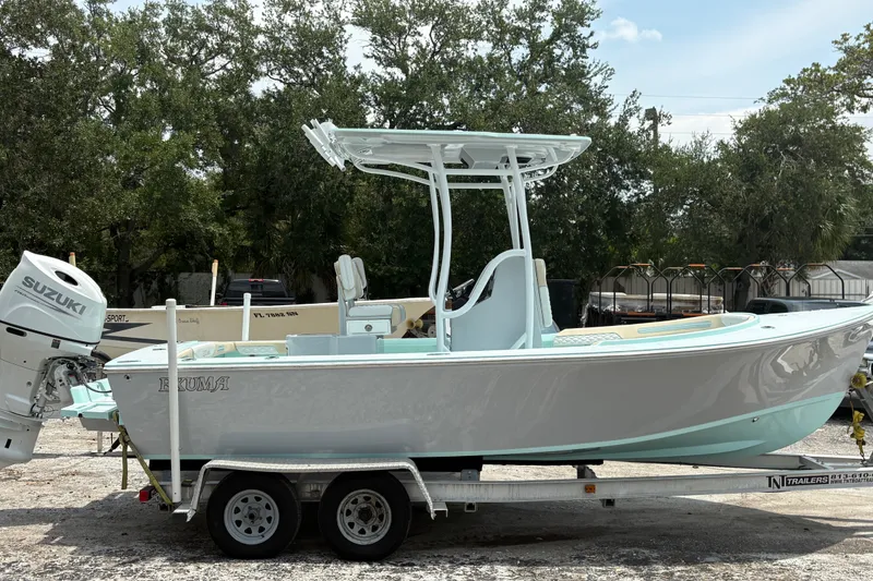 The Image of 2024 Exuma 22 boat on trailer with Suzuki outboard motor, parked outdoors. - 0