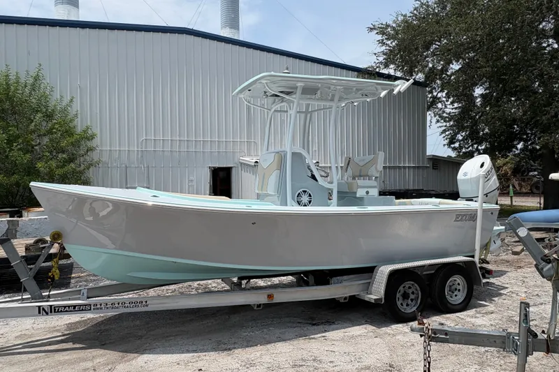 Slide: The Image of 2024 Exuma 22 boat on trailer, parked outdoors near industrial building. - 7