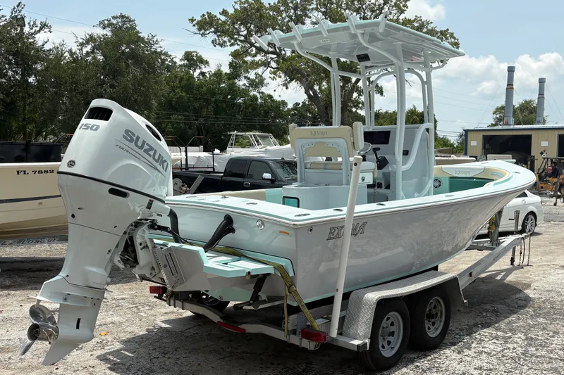 Slide: The Image of 2024 Exuma 22 boat with Suzuki 150 engine on trailer, parked outdoors. - 2