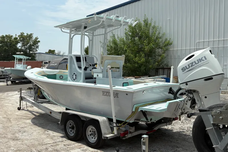 Slide: The Image of 2024 Exuma 22 boat with Suzuki engine on trailer, parked outdoors. - 4