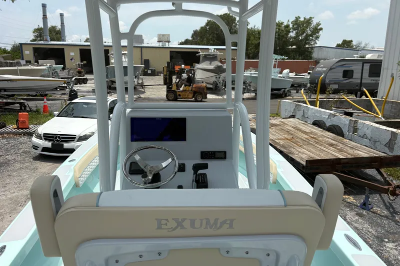 Slide: The Image of 2024 Exuma 22 boat dashboard with steering wheel and display, parked in a marina. - 12