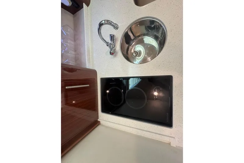 Slide: The Image of Compact kitchen area in a 2015 Regal 35 Sport Coupe with sink and induction cooktop. - 81