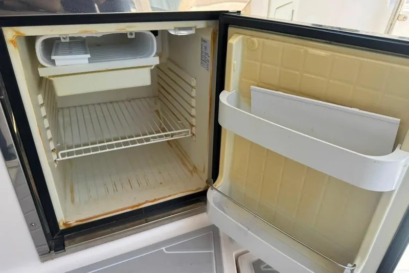 Slide: The Image of Open refrigerator inside a 2015 Regal 35 Sport Coupe boat, showing empty shelves and door compartments. - 87