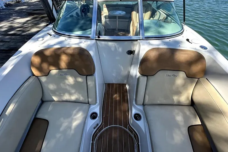 Slide: The Image of 2007 Sea Ray 260 Sundeck interior with tan seating and wood accents, docked by water. - 11
