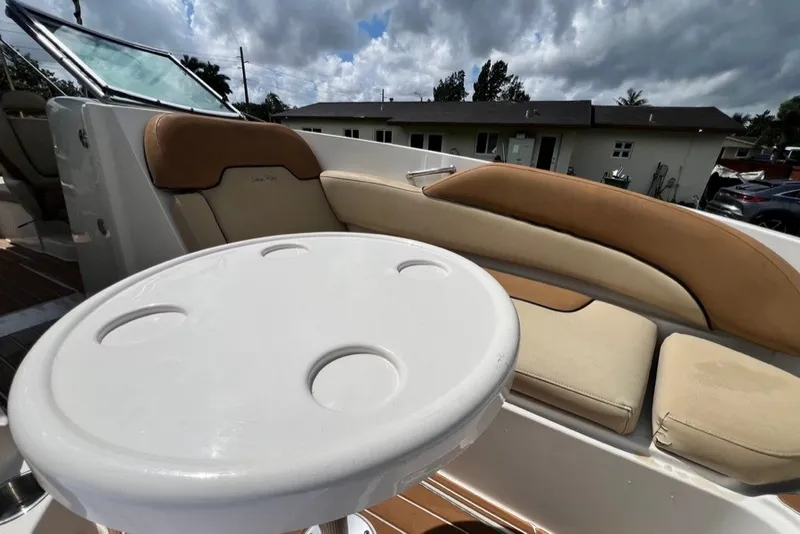 Slide: The Image of 2007 Sea Ray 260 Sundeck interior with cushioned seating and round table under cloudy sky. - 22