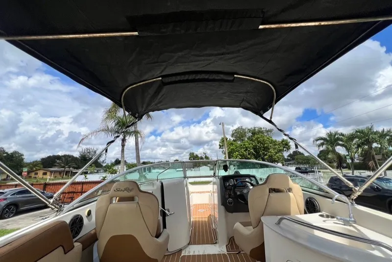 Slide: The Image of 2007 Sea Ray 260 Sundeck interior with canopy, showcasing helm and seating under a blue sky. - 74