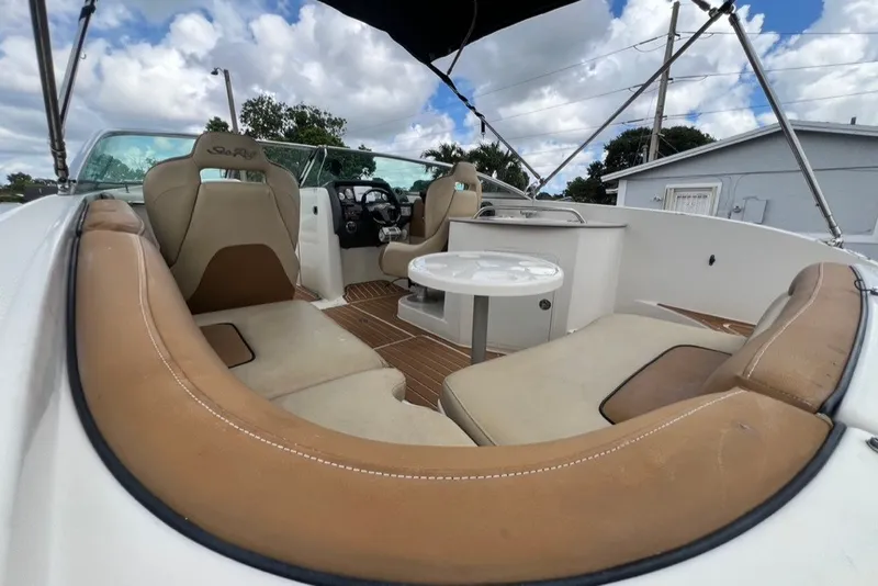 Slide: The Image of 2007 Sea Ray 260 Sundeck interior with tan seating and table under a cloudy sky. - 75