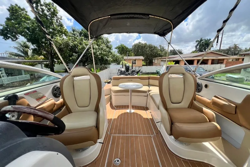Slide: The Image of 2007 Sea Ray 260 Sundeck interior with tan seating and canopy, parked outdoors. - 37