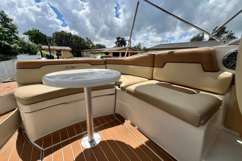 Slide: The Image of 2007 Sea Ray 260 Sundeck interior with cushioned seating and table under cloudy sky. - 32