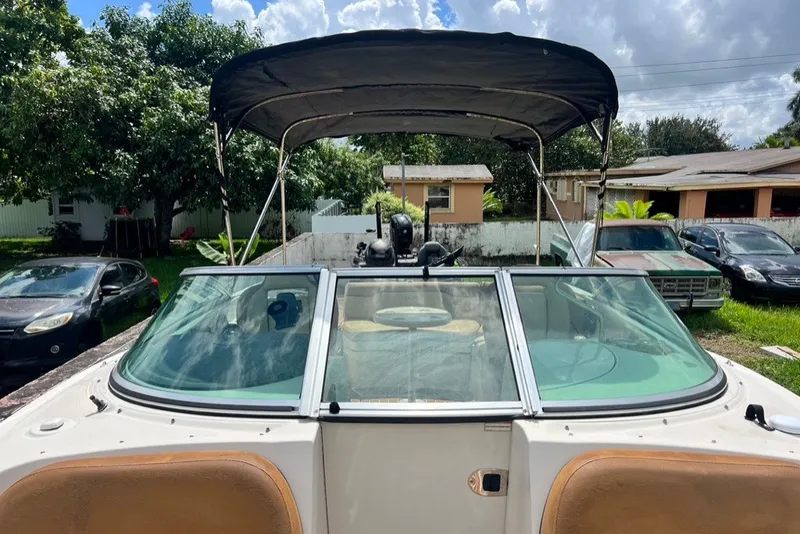 Slide: The Image of 2007 Sea Ray 260 Sundeck boat with canopy, parked outdoors near cars and trees. - 41