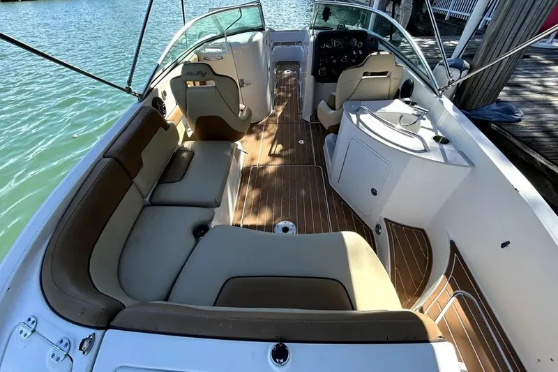 Slide: The Image of 2007 Sea Ray 260 Sundeck interior with beige seating and wooden flooring, docked by water. - 7